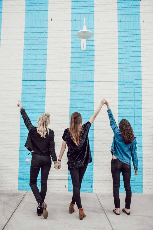 trois jeunes femmes devant un mur